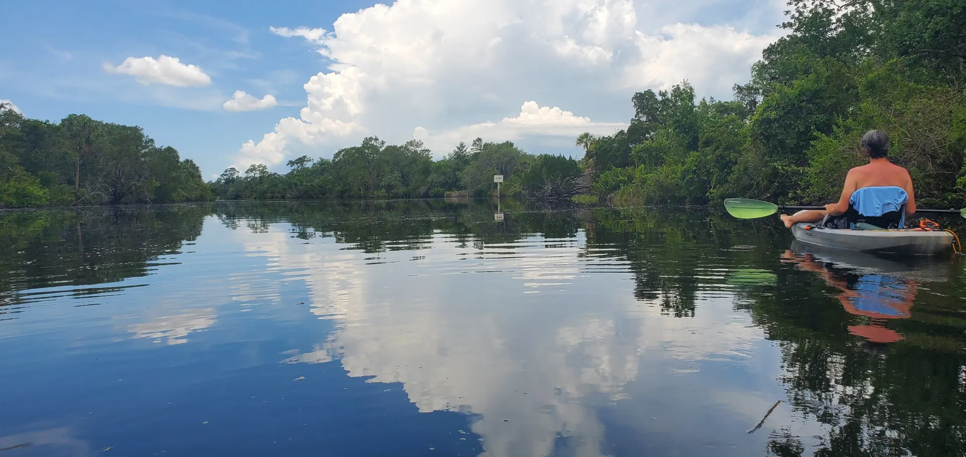 A person in a kayak on a clam river.